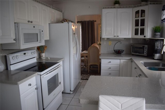 kitchen featuring light tile patterned flooring, white cabinets, white appliances, and backsplash