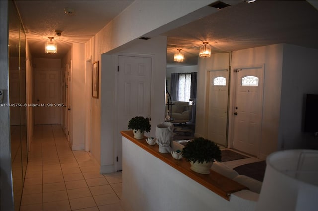 foyer entrance featuring light tile patterned floors and a textured ceiling