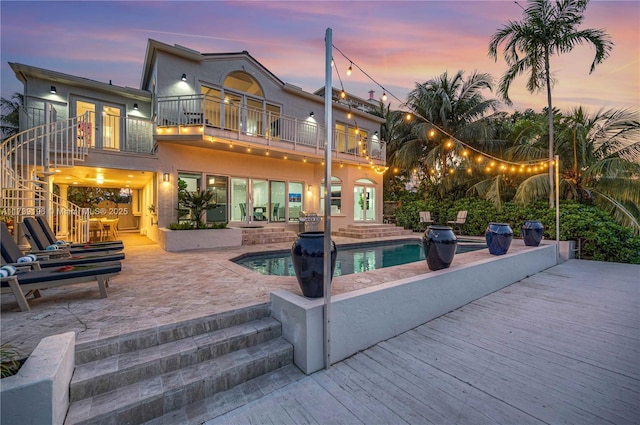 back house at dusk with a patio area and a balcony