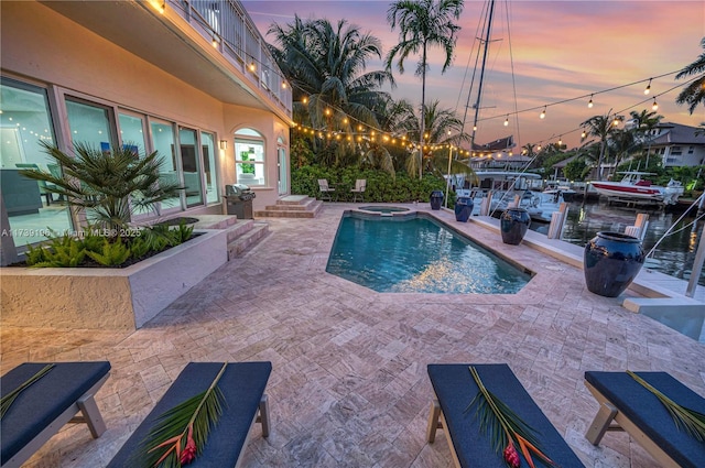 pool at dusk featuring an in ground hot tub, grilling area, and a patio area