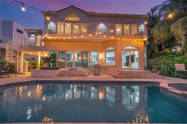 back house at dusk with a patio and a balcony