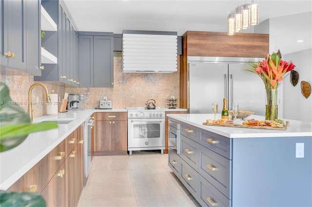 kitchen featuring light tile patterned floors, sink, hanging light fixtures, premium appliances, and decorative backsplash