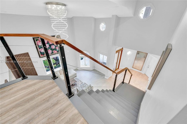 staircase with a notable chandelier, hardwood / wood-style floors, and a high ceiling