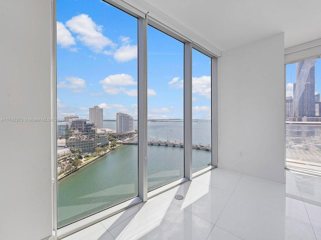 tiled empty room with plenty of natural light, a view of city, and a water view