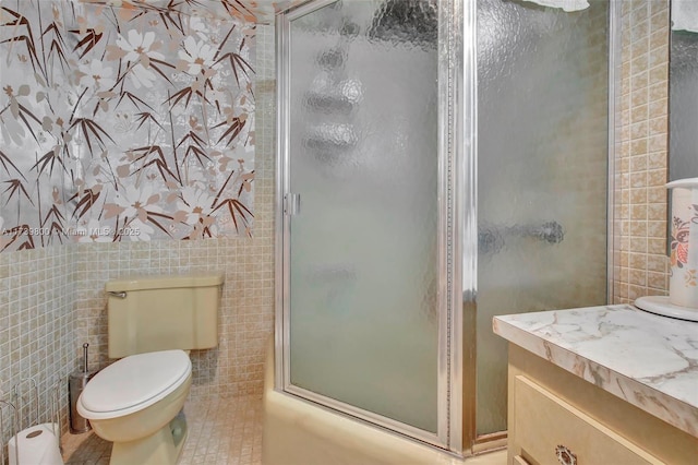 full bathroom with vanity, tile walls, shower / bath combination with glass door, and toilet