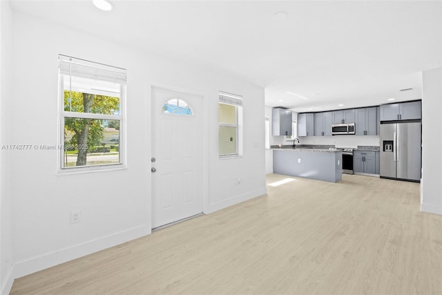 unfurnished living room with sink and light hardwood / wood-style floors