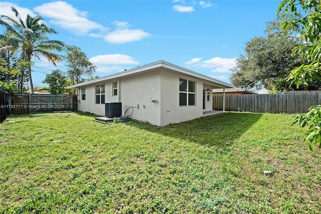 back of property with a yard and central AC