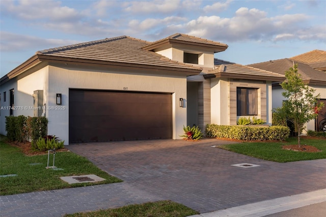 view of front of property featuring a garage, decorative driveway, and stucco siding