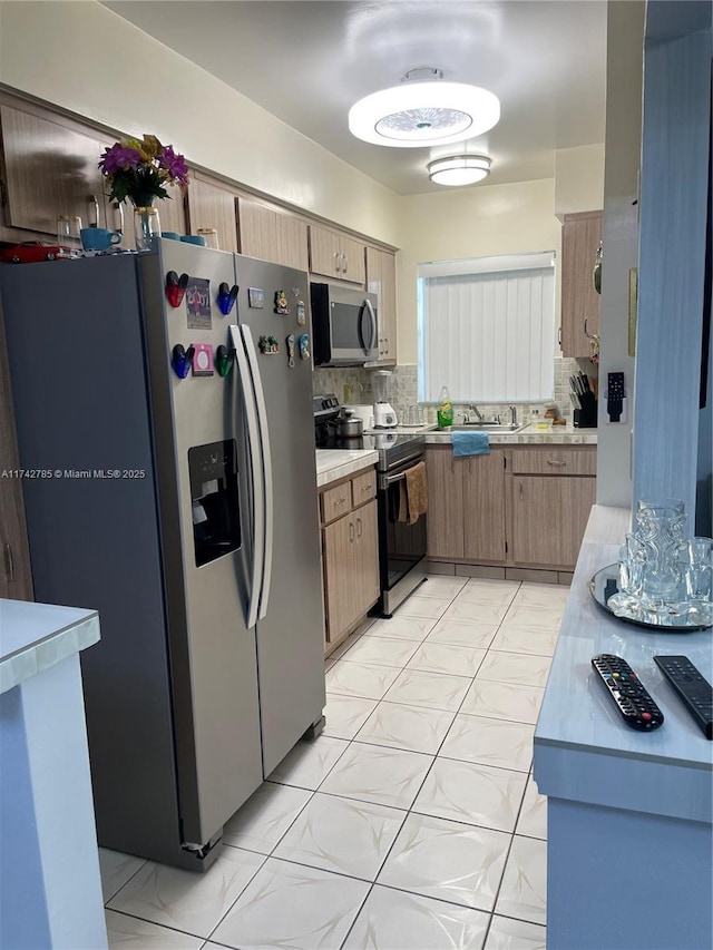 kitchen featuring decorative backsplash, appliances with stainless steel finishes, light countertops, and a sink