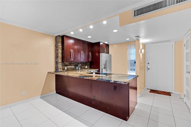 kitchen featuring light tile patterned floors, stone counters, stainless steel refrigerator with ice dispenser, decorative backsplash, and kitchen peninsula