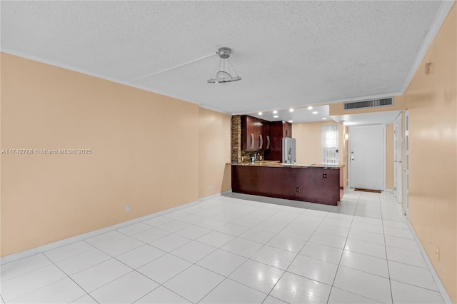 interior space featuring decorative light fixtures, stainless steel fridge, light tile patterned floors, kitchen peninsula, and a textured ceiling