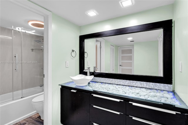 full bathroom featuring enclosed tub / shower combo, hardwood / wood-style floors, vanity, and toilet