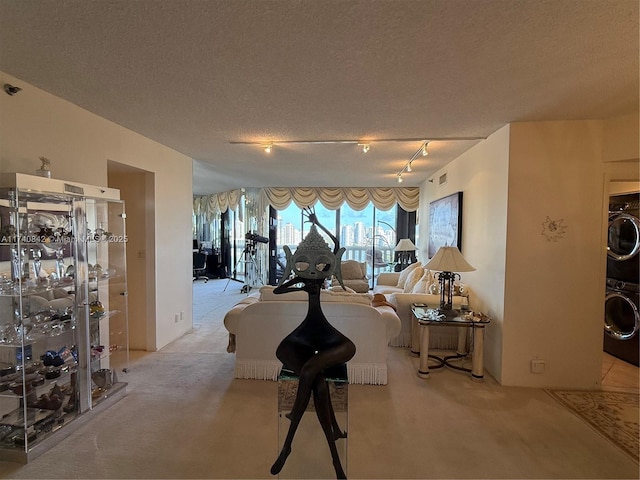 interior space featuring stacked washer and dryer, track lighting, light carpet, and a textured ceiling