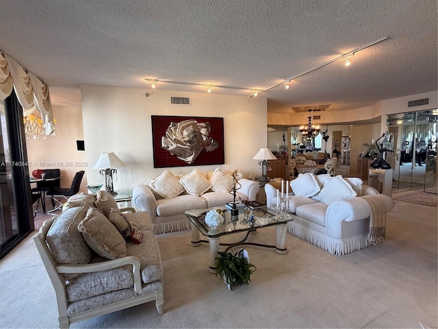 living room with track lighting, a chandelier, carpet, and a textured ceiling