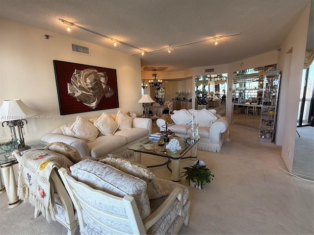 living room with track lighting, light colored carpet, a chandelier, and a textured ceiling