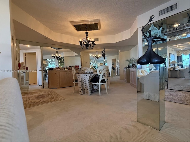 dining area featuring a tray ceiling, a textured ceiling, light carpet, and a notable chandelier