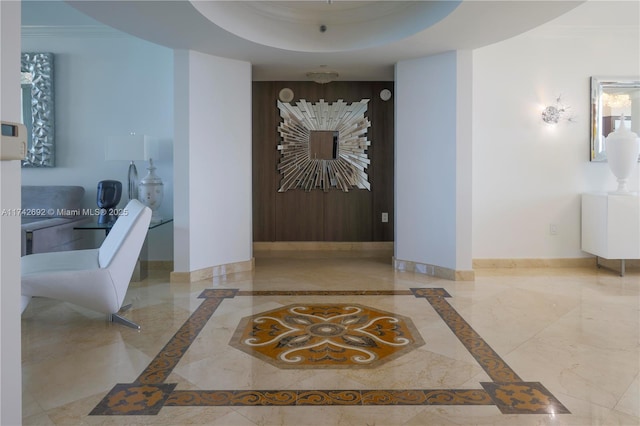 hallway with ornamental molding and a tray ceiling