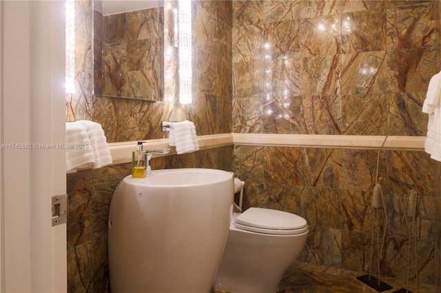 bathroom with toilet and tile walls