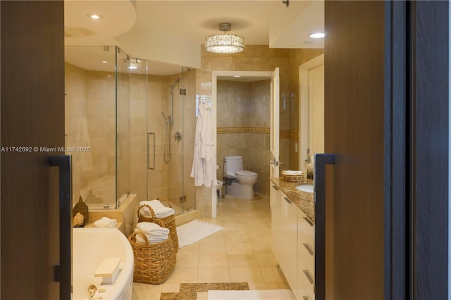 bathroom with tile walls, tile patterned flooring, vanity, an enclosed shower, and toilet