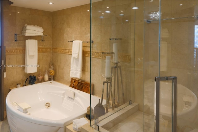 bathroom featuring tile walls and independent shower and bath