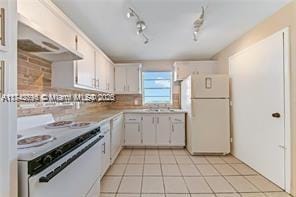 kitchen featuring light tile patterned floors, white appliances, white cabinets, and backsplash