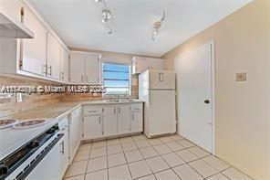 kitchen with white cabinetry, white refrigerator, tasteful backsplash, light tile patterned flooring, and exhaust hood