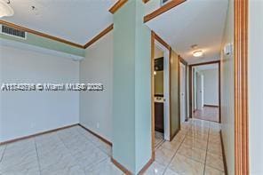 hallway featuring light tile patterned floors and crown molding