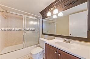 full bathroom with bath / shower combo with glass door, vanity, toilet, and tile patterned flooring