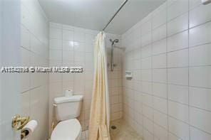 bathroom with tile walls, toilet, and walk in shower