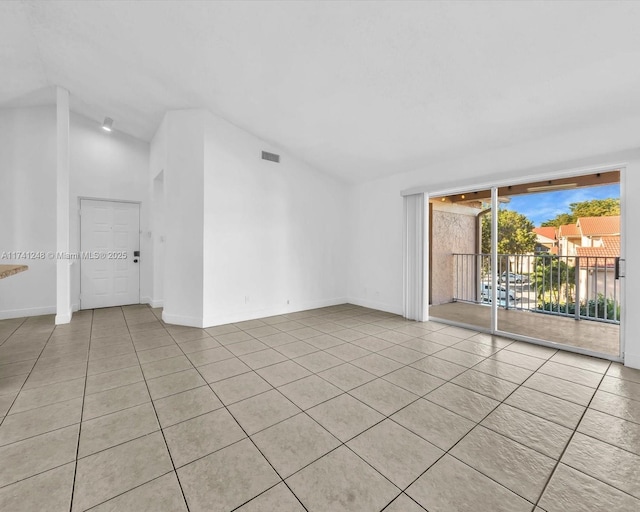 unfurnished room with lofted ceiling and light tile patterned floors