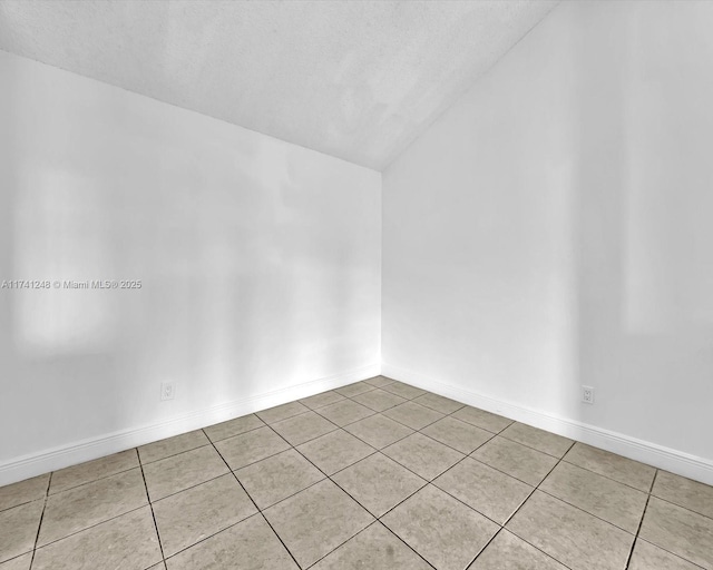 tiled spare room with vaulted ceiling and a textured ceiling