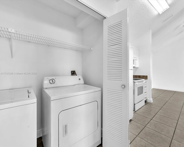 laundry area with separate washer and dryer and light tile patterned floors