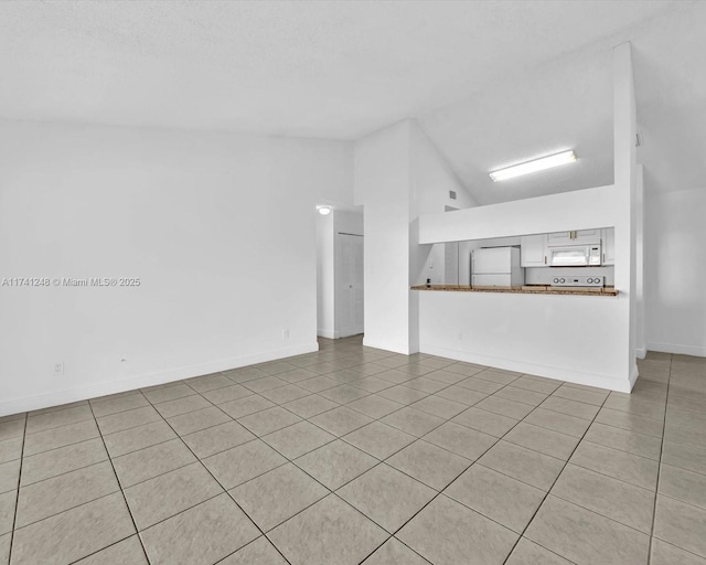 unfurnished living room with lofted ceiling and light tile patterned floors