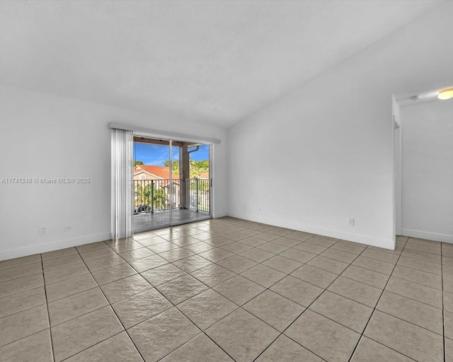 spare room with light tile patterned floors and vaulted ceiling