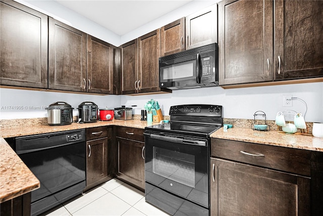 kitchen featuring dark brown cabinetry, light stone countertops, light tile patterned floors, and black appliances