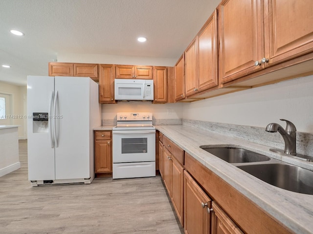 kitchen featuring sink, light wood-type flooring, white appliances, light stone countertops, and a textured ceiling