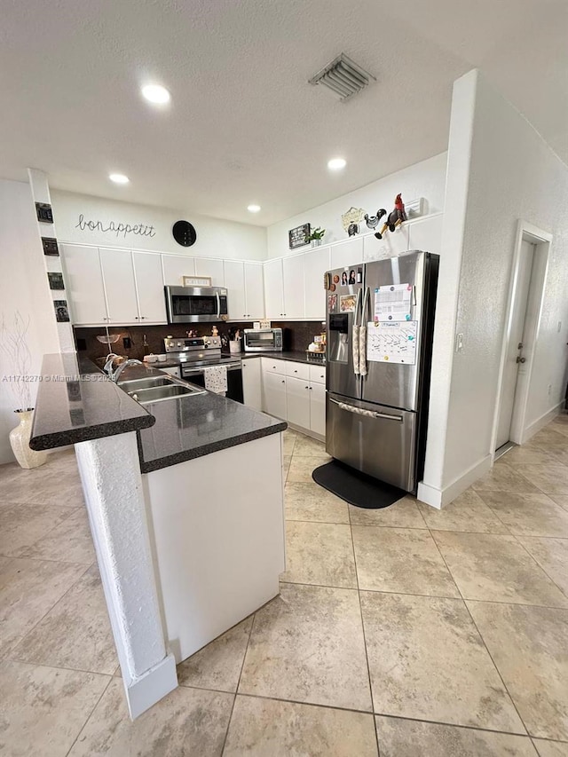 kitchen with sink, white cabinets, decorative backsplash, kitchen peninsula, and stainless steel appliances