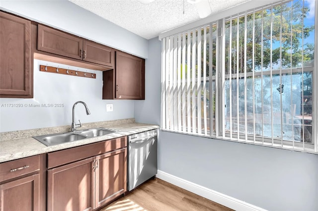 kitchen featuring sink, stainless steel dishwasher, a textured ceiling, and light hardwood / wood-style flooring