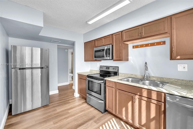 kitchen with light hardwood / wood-style flooring, sink, stainless steel appliances, and a textured ceiling