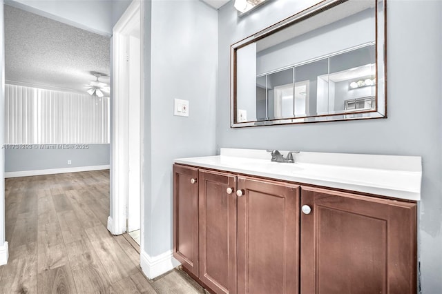 bathroom with hardwood / wood-style flooring, ceiling fan, vanity, and a textured ceiling