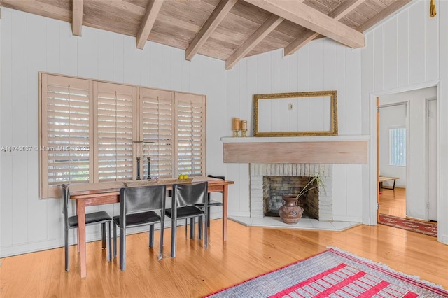 dining room with wood ceiling, lofted ceiling with beams, a brick fireplace, and hardwood / wood-style flooring