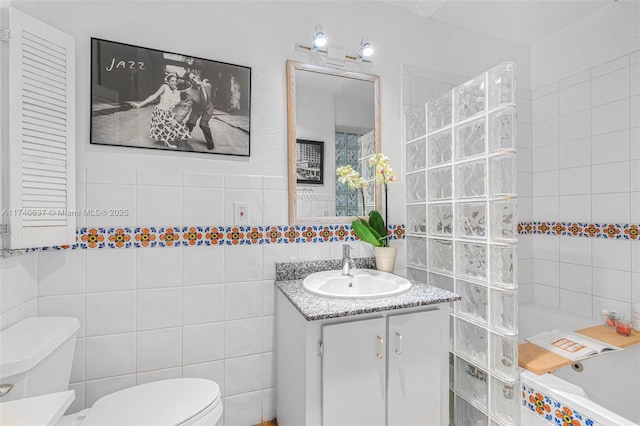 bathroom featuring vanity, a tub, tile walls, and toilet