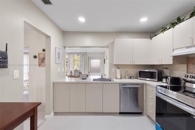 kitchen featuring stainless steel appliances, light countertops, under cabinet range hood, white cabinetry, and a sink