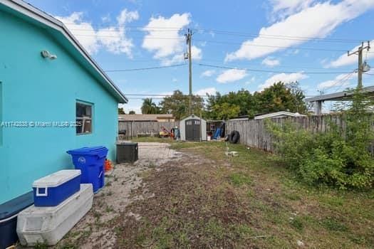 view of yard with an outbuilding, a fenced backyard, and a shed