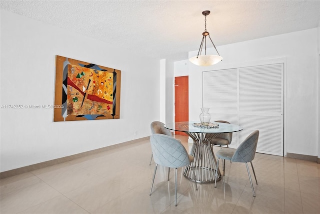 dining room with a textured ceiling, light tile patterned flooring, and baseboards