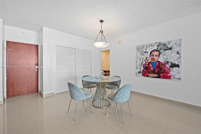 dining room with light tile patterned floors, baseboards, and a textured ceiling