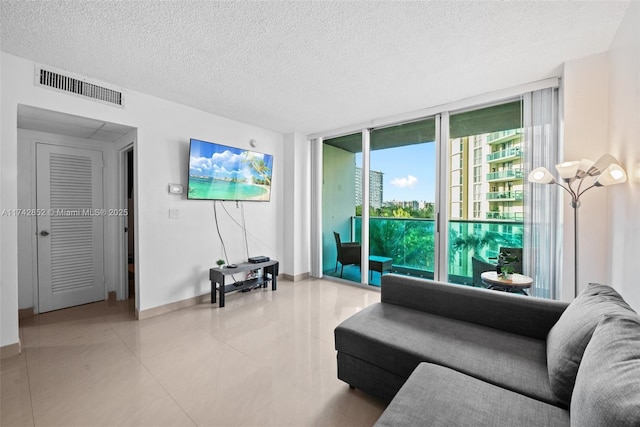 living room with baseboards, visible vents, a wall of windows, a textured ceiling, and light tile patterned flooring