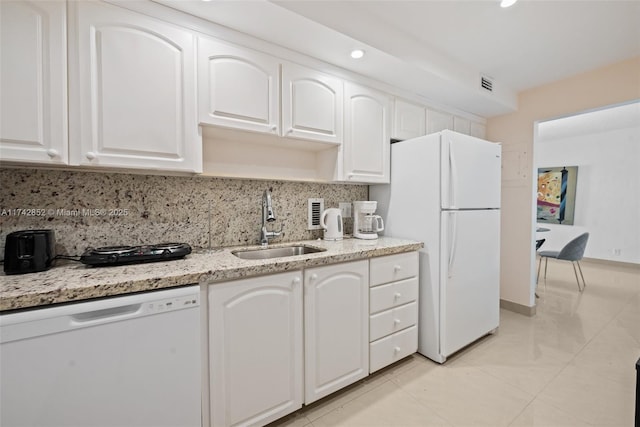 kitchen with white appliances, white cabinets, a sink, light stone countertops, and backsplash