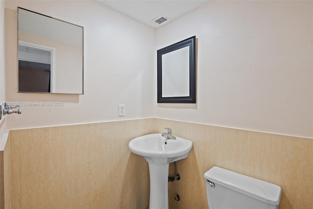 bathroom featuring a wainscoted wall, visible vents, a sink, and toilet