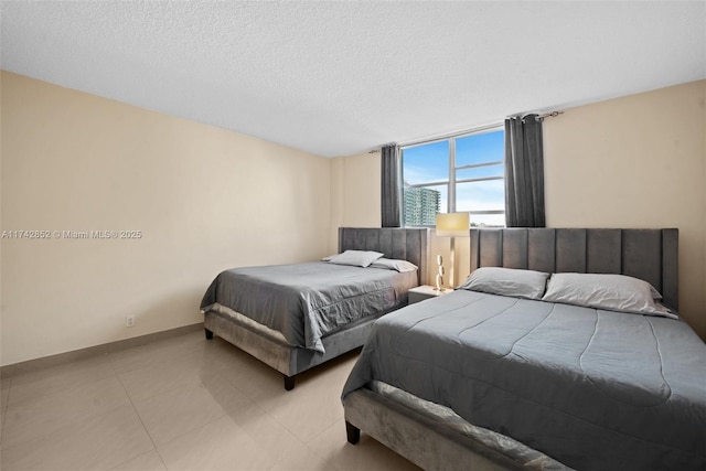 bedroom featuring light tile patterned floors, a textured ceiling, and baseboards